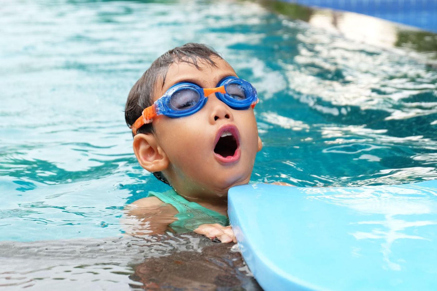 A boy in swimming goggles swimming in a pool