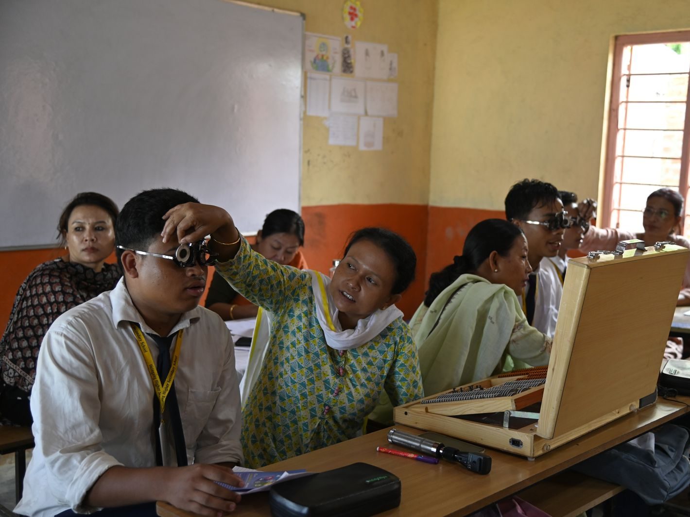 A health worker checking a student's vision with a trial frame during a school eye screening
